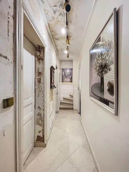 Grand couloir blanc lumineux menant aux différentes pièces d'une maison en viager.