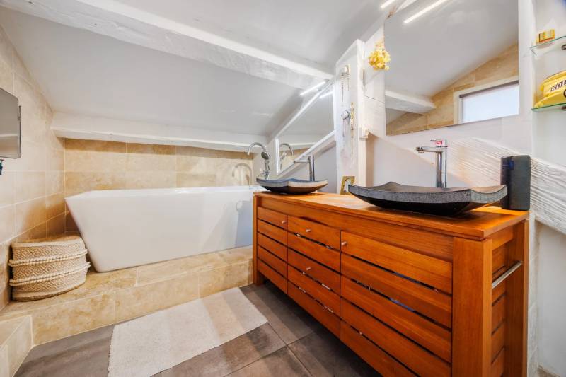 Salle de bain moderne avec baignoire encastrée et vasques en pierre naturelle, appartement Marseille Castellane